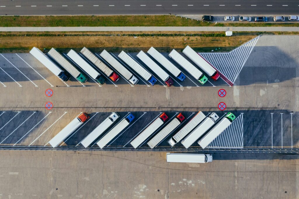 Aerial view of semi-trucks with trailers parked in angled rows at a distribution center lot