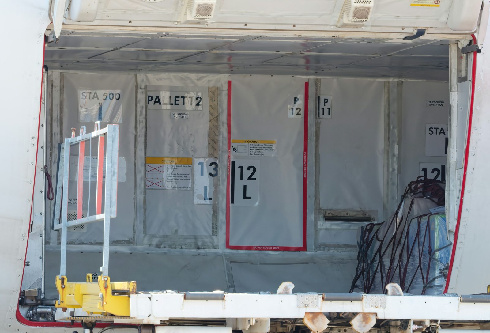 Interior of an aircraft cargo hold with marked pallet positions and a loaded cargo net
