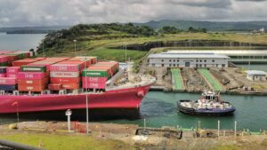 Container ship guided by a tugboat through the Panama Canal locks