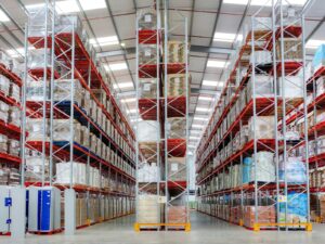 Aisle of a fulfillment warehouse with tall red pallet racking holding palletized consumer goods