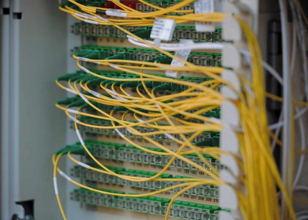 Yellow fiber optic patch cables connected to a labeled distribution panel in a network rack