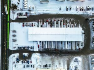 Aerial view of a cross-dock freight terminal with trailers backed into dock doors on both sides