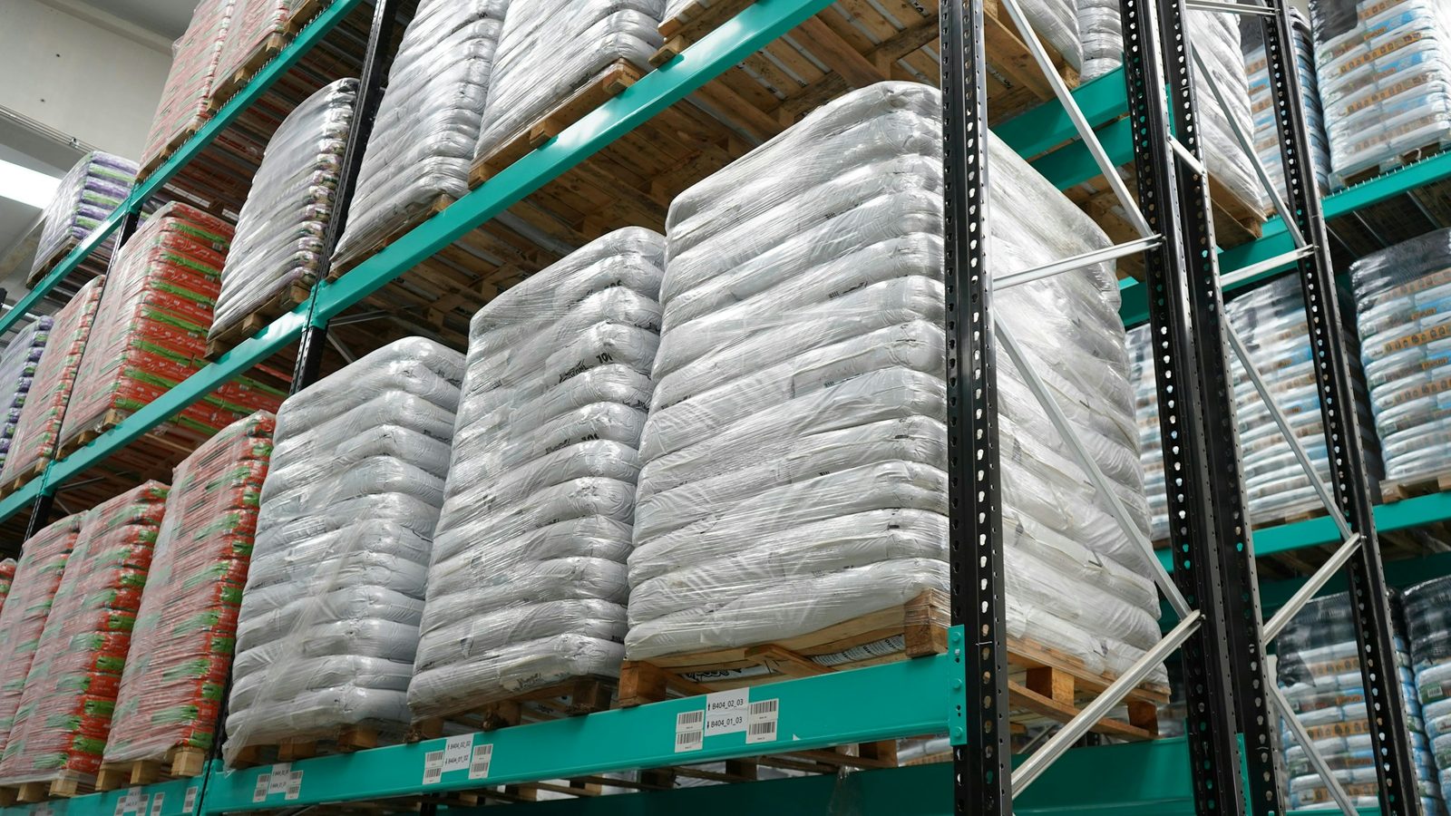 Shrink-wrapped pallets with identification labels stored on warehouse racking